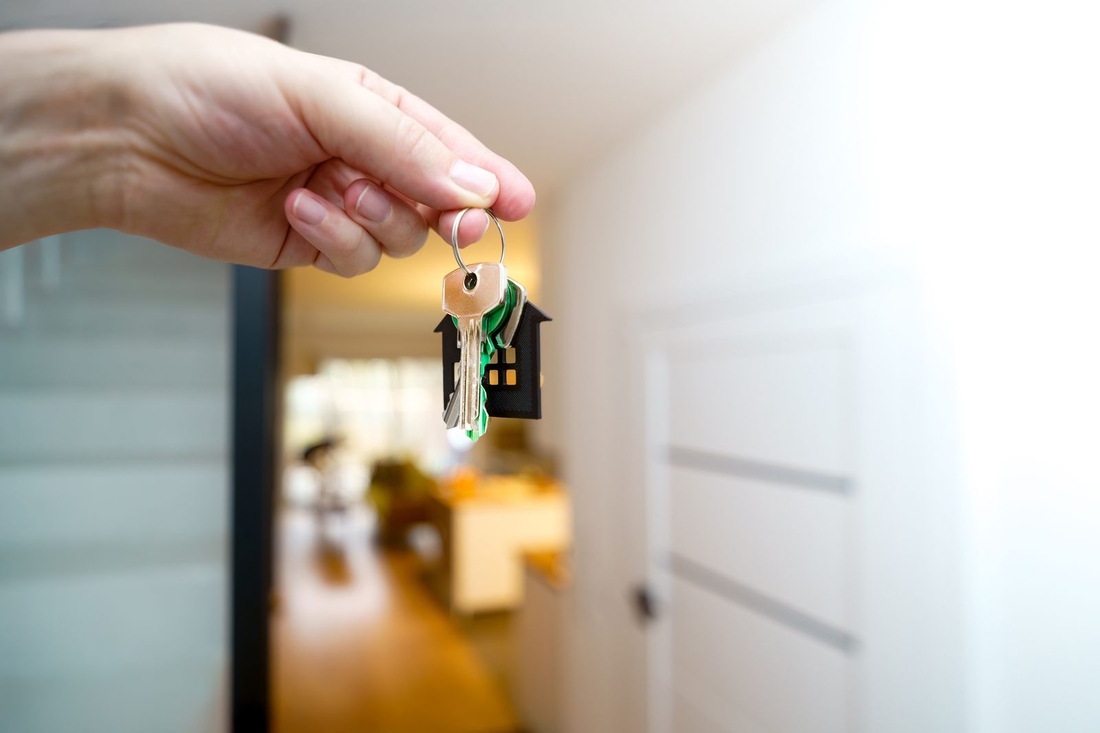 Hand met huissleutels voor de deur van een nieuwe woning