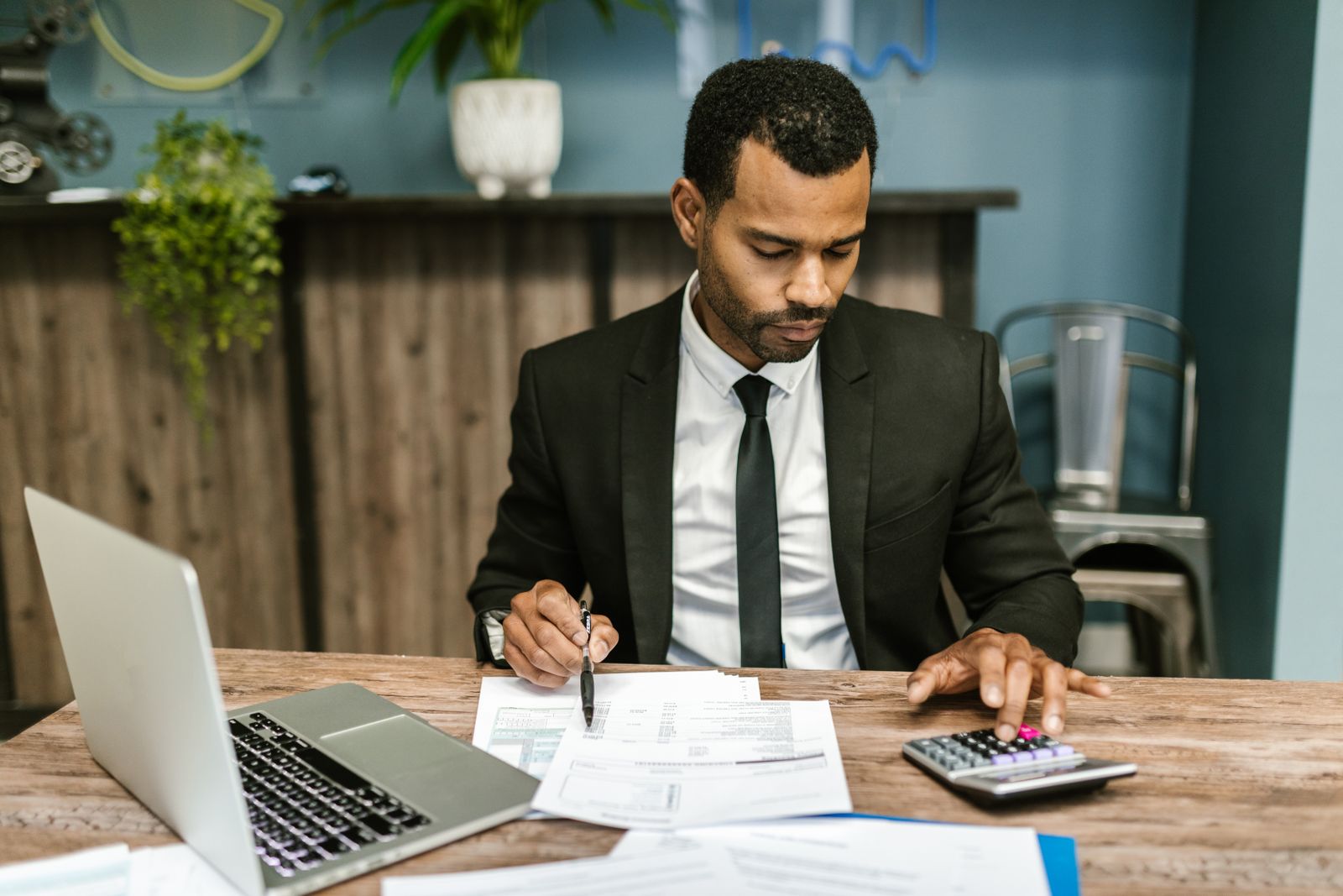 Ondernemer aan een bureau met laptop, rekenmachine en papieren administratie