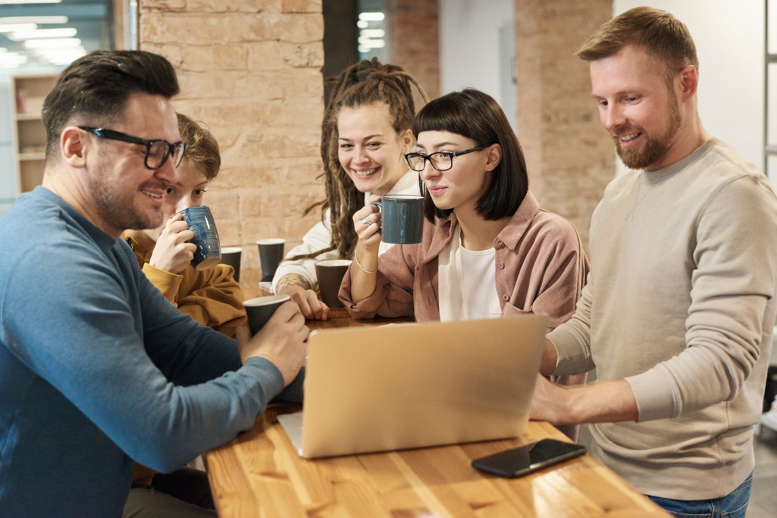 Collega's met koffie kijken samen naar een laptop: het incassobestand nalopen voordat het naar de bank gaat